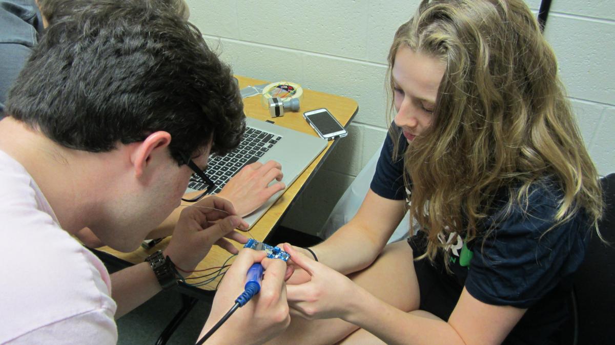 [Justin and Emma soldering the arduino board to the motor shield]