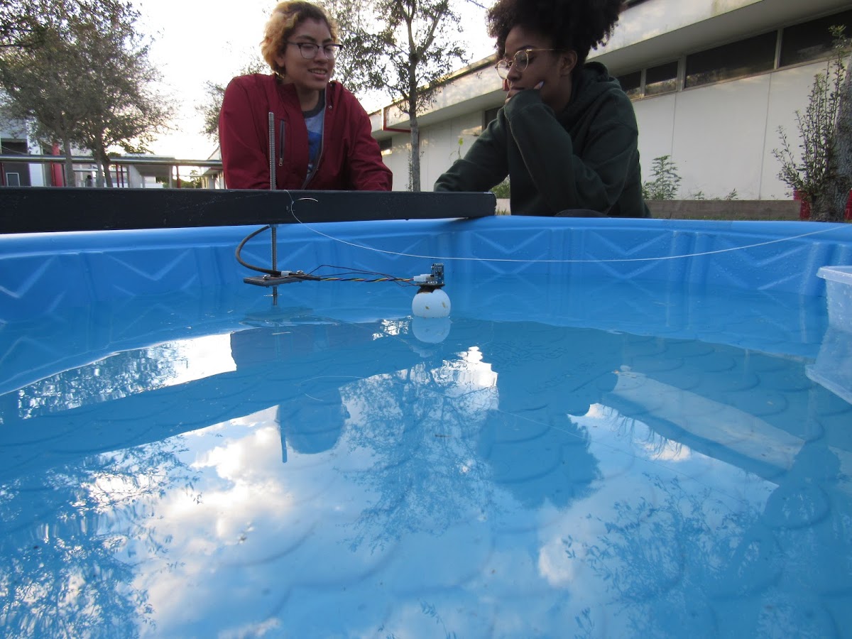 Two members work on coding by a children's pool containing the experiment.
